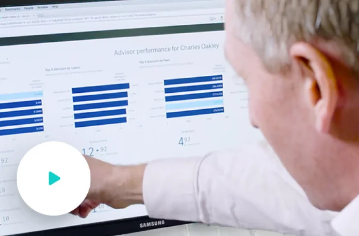 A person is pointing at a computer screen displaying performance metrics and bar graphs for an advisor.