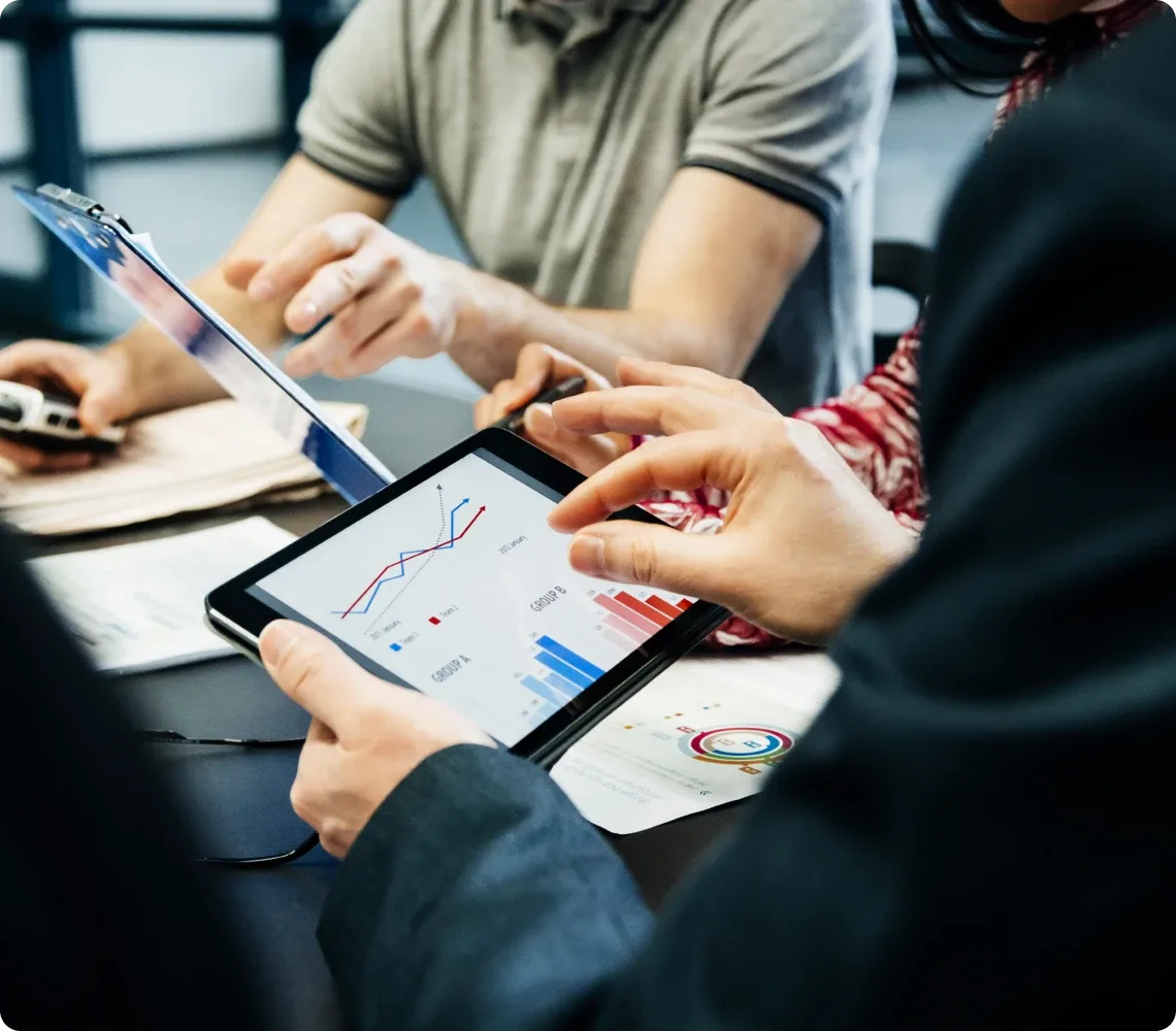 People reviewing financial charts and data on a tablet and laptop.