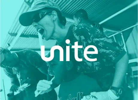 A person wearing gloves helps a child brush their teeth as another person does the same in the background. The word "unite" is overlaid on the image.