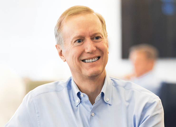 Headshot of Qlik Board of Directors member, James Lines. He has short blonde hair, is wearing a light blue collared shirt, and is smiling. The background is blurred.