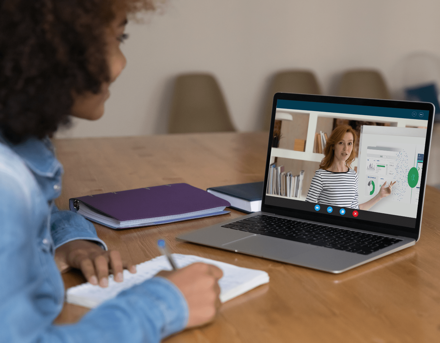 A woman at a desk with a laptop and phone, participating in instructor-led training with Qlik experts.