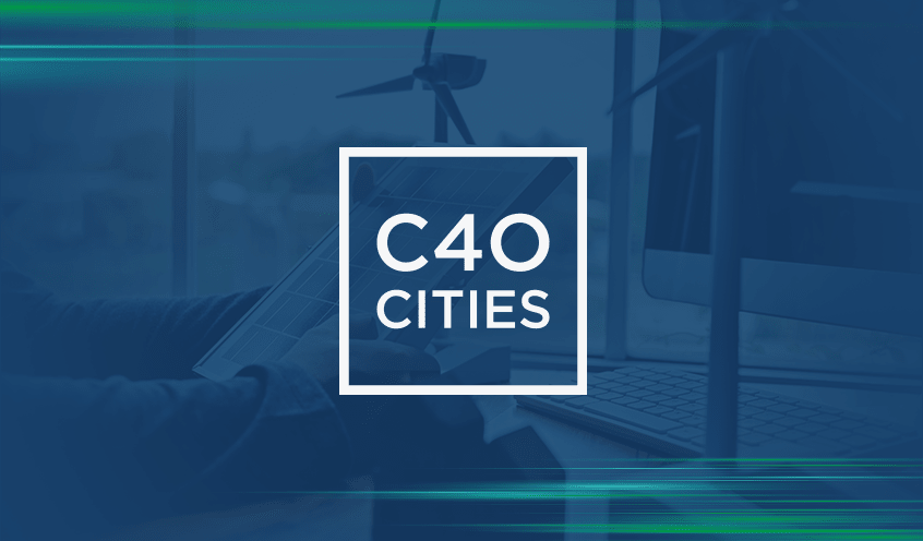 C40 Cities logo over an image of a person working on a tablet with wind turbines and a computer screen in the background.