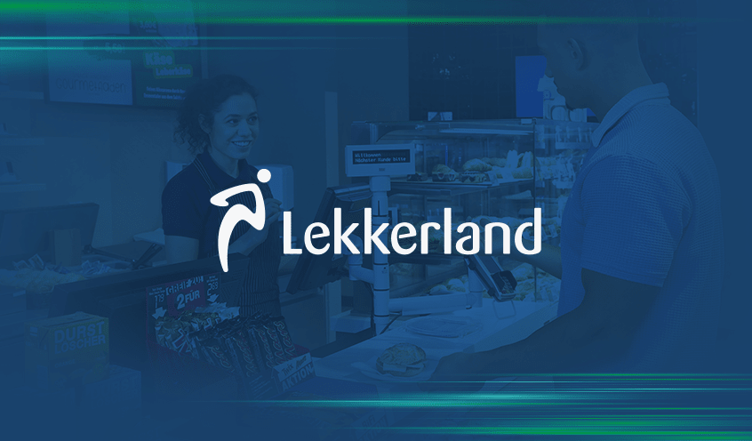 A woman cashier at a Lekkerland store smiles at a male customer as he stands at the counter with a snack. The Lekkerland logo is prominently displayed over the image.