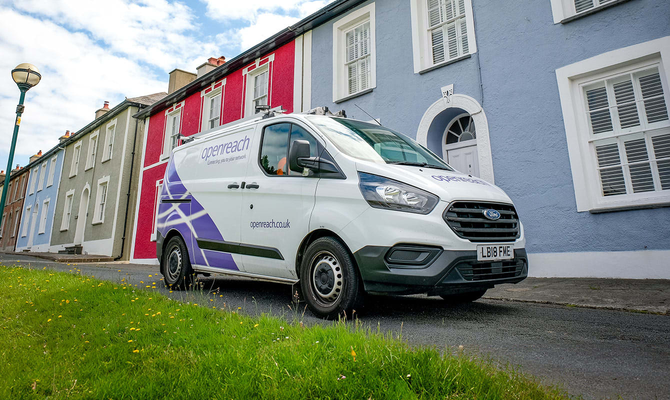 A white van with Openreach logo is parked on a street beside a row of colorful houses. 