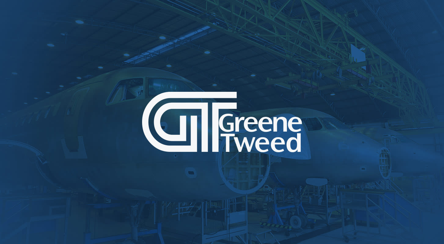 Greene Tweed logo over a background of airplane construction in a large industrial hanger.